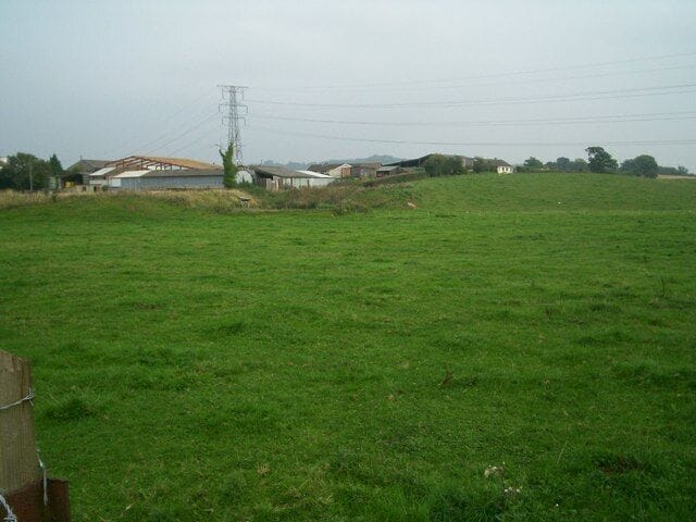 Pen-y-Parc Farm. Looking across grassy field to Pen-y-Parc farm, with power lines passing above.