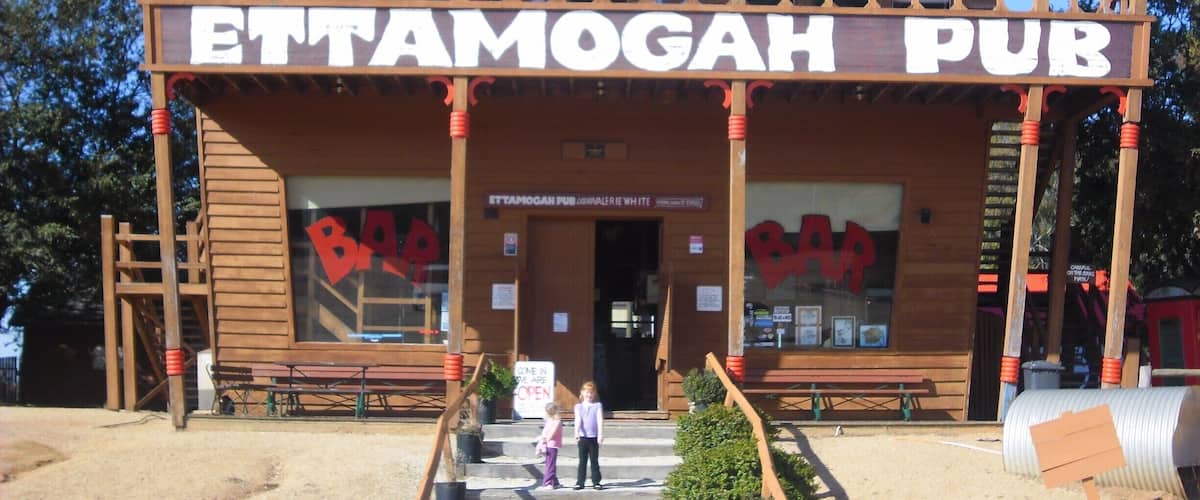 A wooden building with a red roof and the sign "Ettamogah Pub".