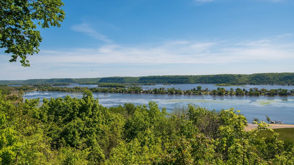 A river surrounded by dense green forest and hills.