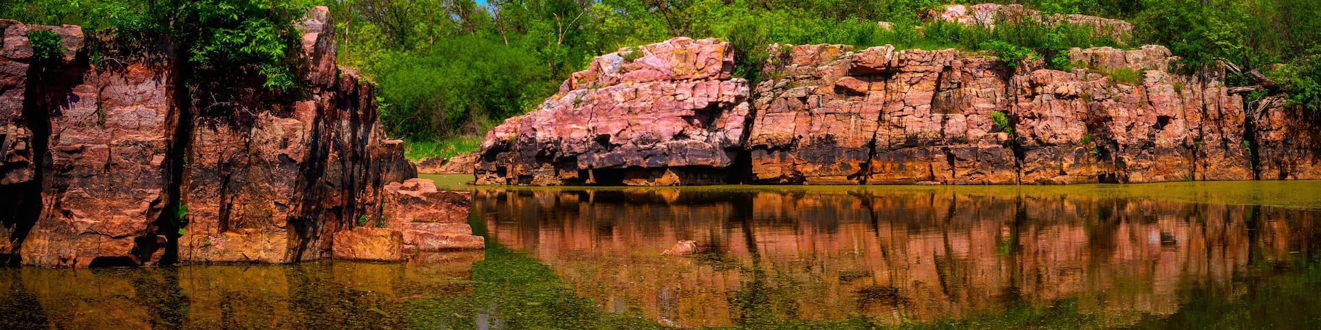 Quartzite red rock excavation site remains at Gitchie Manitou State Preserve and Nature Conservation Areas, a tranquil spring landscape in Larchwood, Iowa, USA