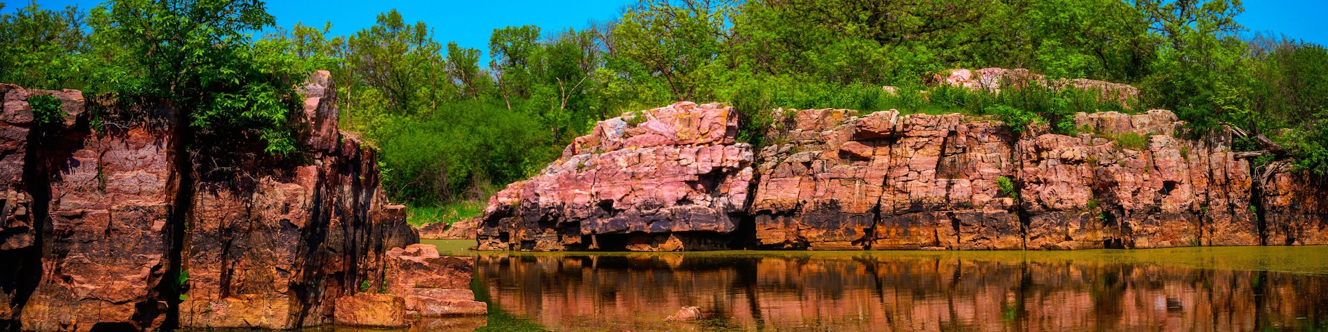 Quartzite red rock excavation site remains at Gitchie Manitou State Preserve and Nature Conservation Areas, a tranquil spring landscape in Larchwood, Iowa, USA
