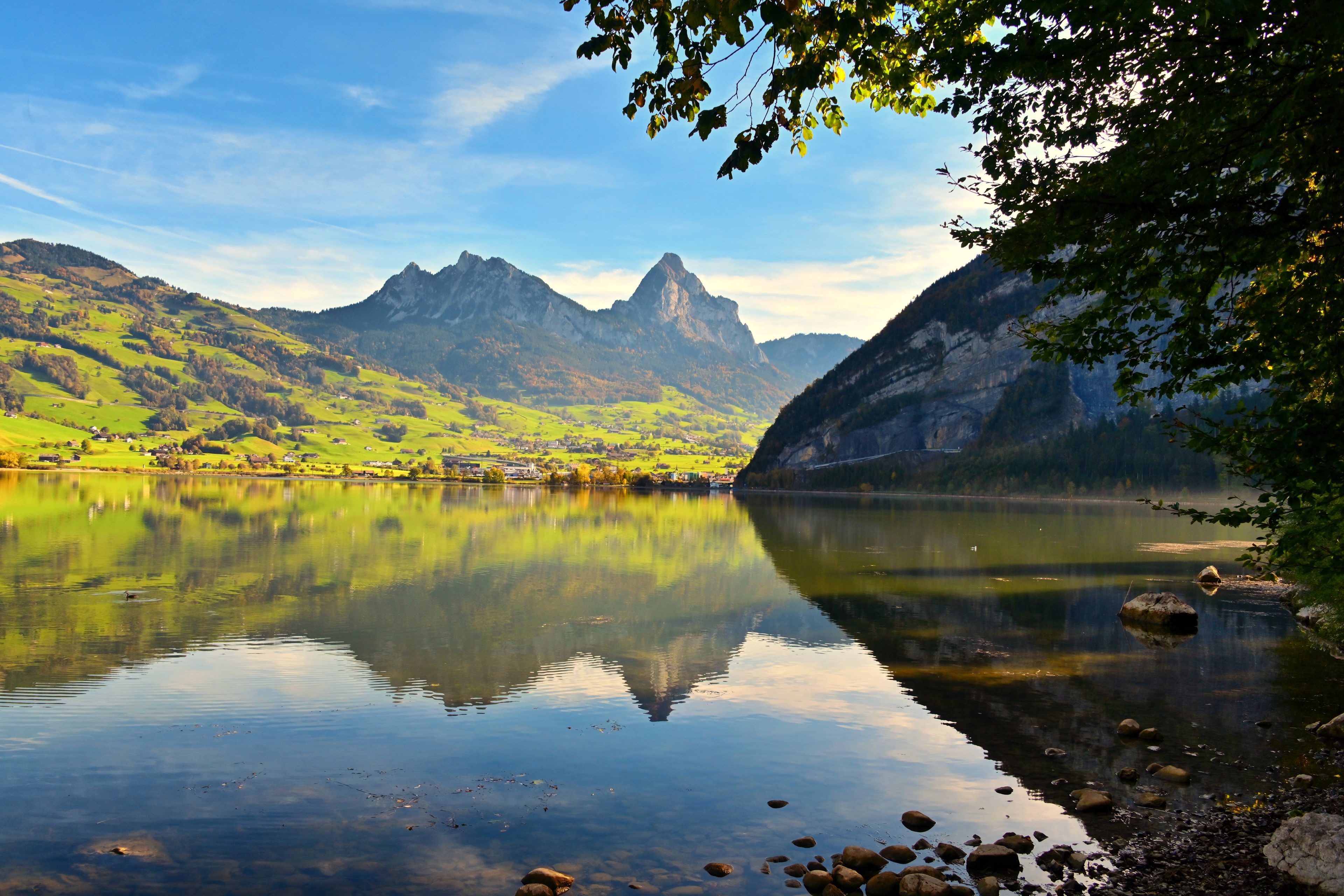 A tranquil lake surrounded by green hills and mountains.