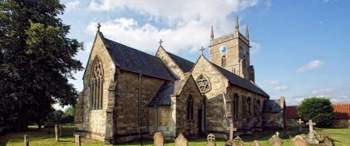 A historic church with a large steeple and multiple tombstones in the foreground.