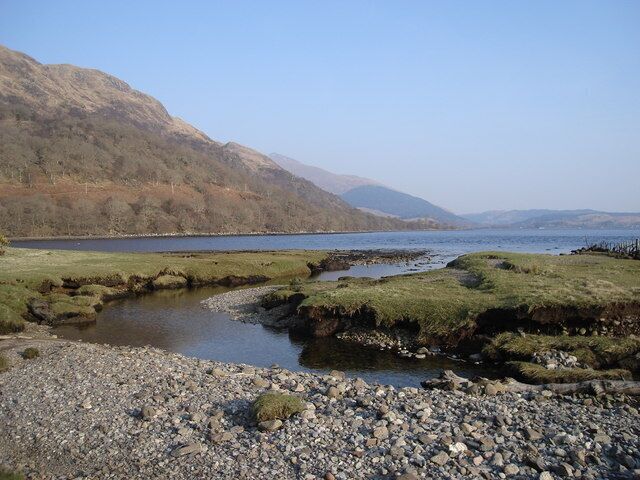 A calm lake with rocky shores and distant mountains.