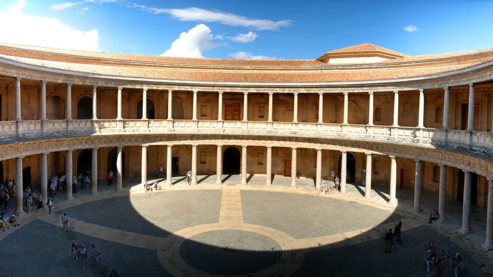 A large, open courtyard with a central circular area, surrounded by multiple levels of arches and columns.