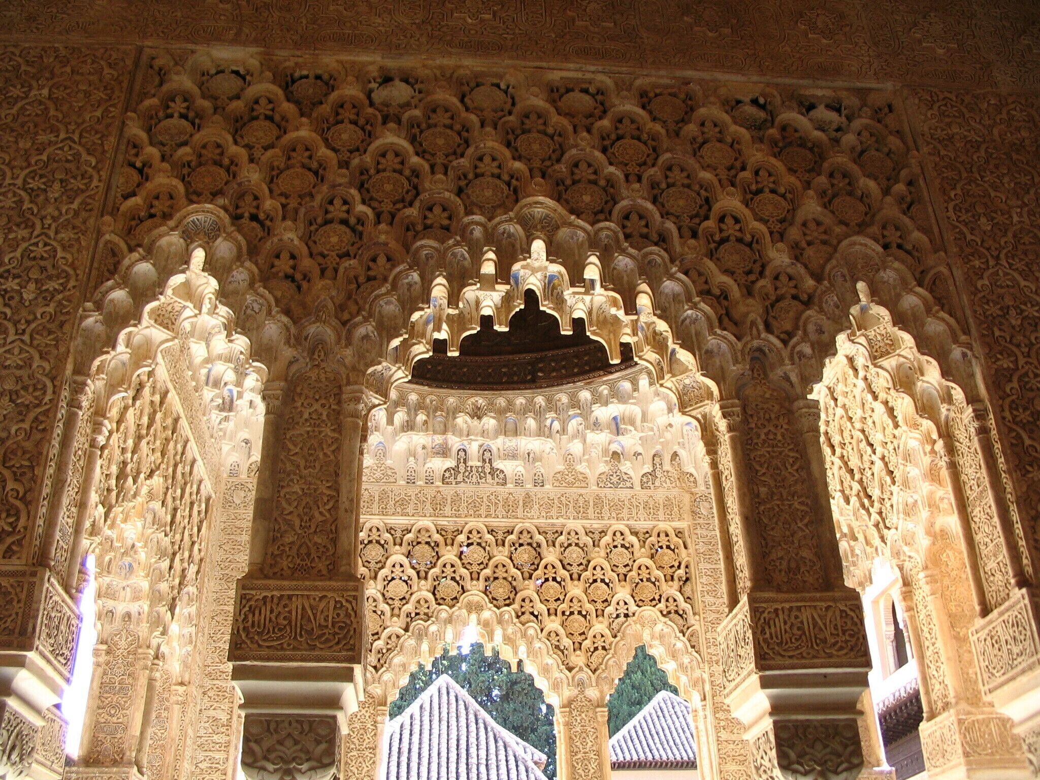 An intricately carved archway with detailed geometric and floral patterns, surrounded by ornate columns and a richly decorated ceiling.
