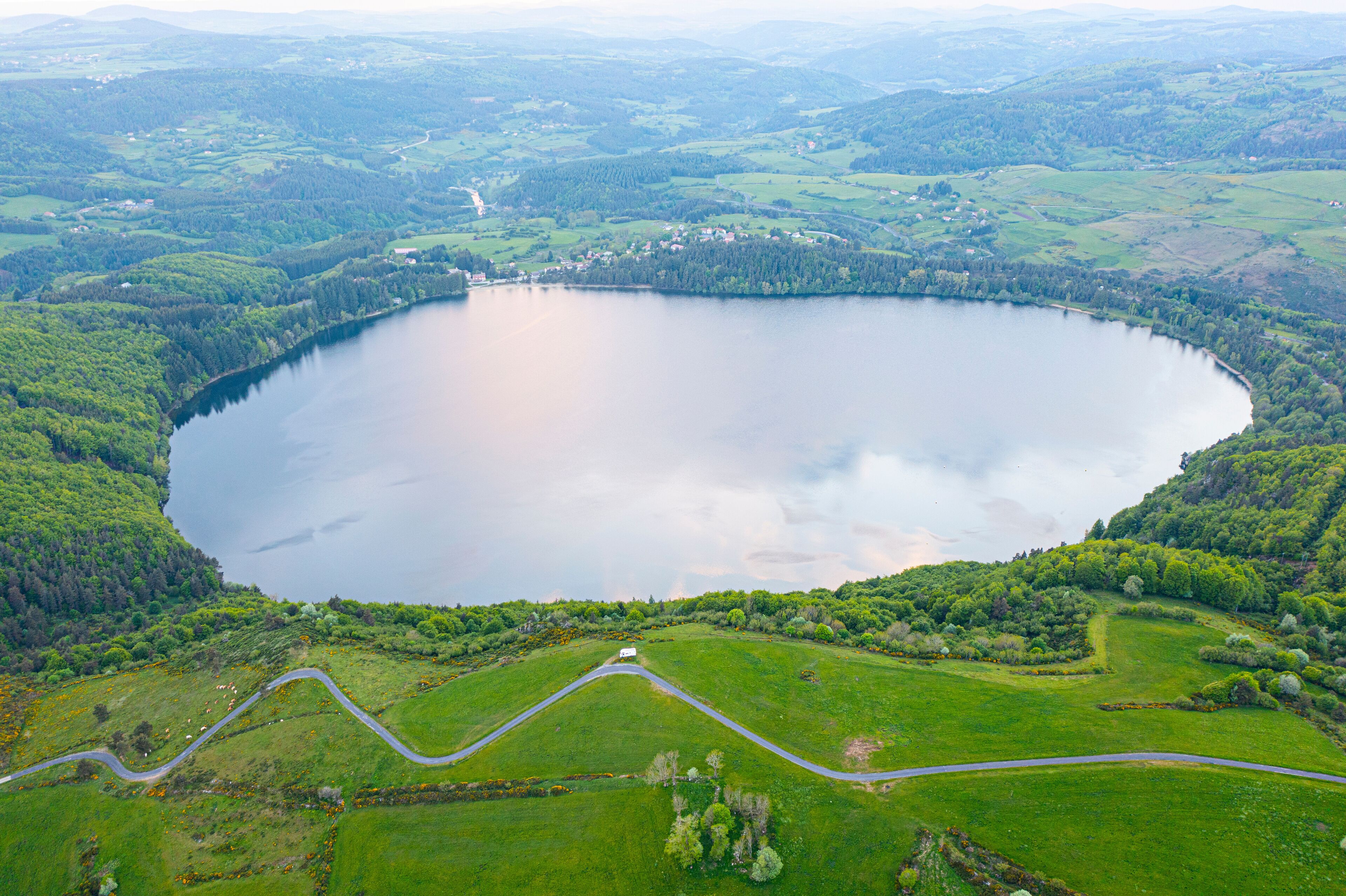 A large lake surrounded by green hills and a winding road.