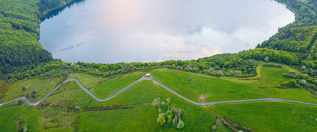A large lake surrounded by green hills and a winding road.