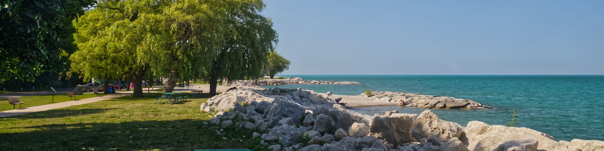 A picnic table by a rocky shoreline with a clear blue sky.