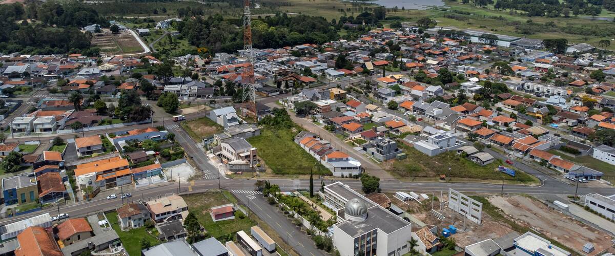 An aerial view of a residential area with houses, roads, and a large body of water in the background.