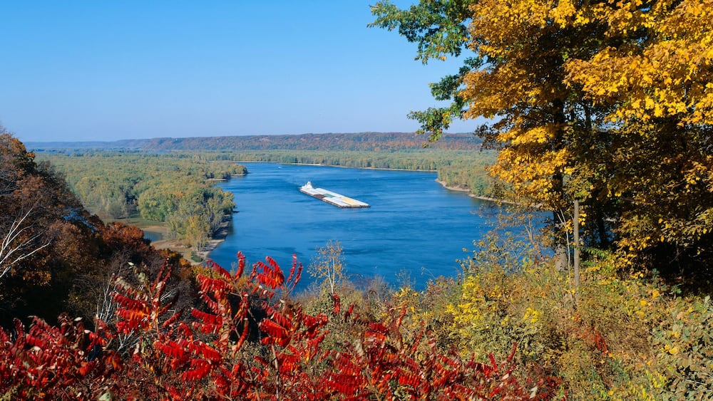 A river with a ship, surrounded by autumn foliage.