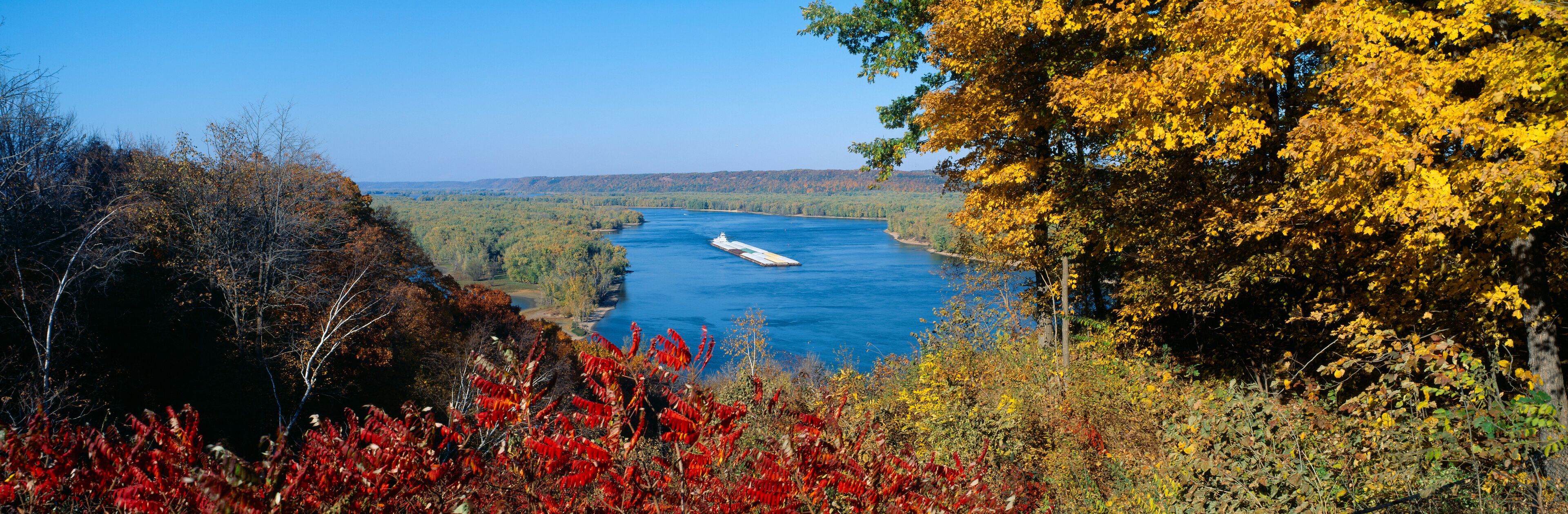 A river with a ship, surrounded by autumn foliage.
