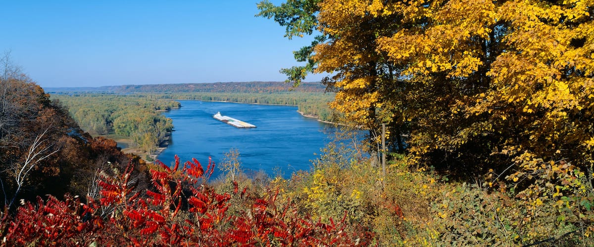 A river with a ship, surrounded by autumn foliage.