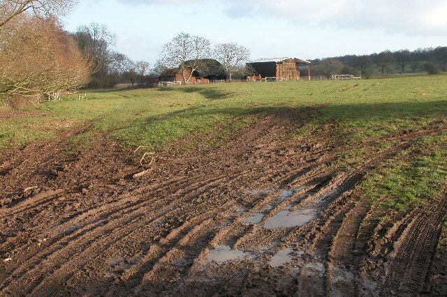 A muddy field with a barn in the background.