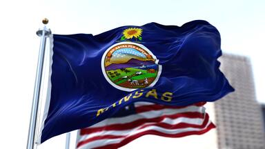 the flag of the US state of Kansas waving in the wind with the American flag blurred in the background