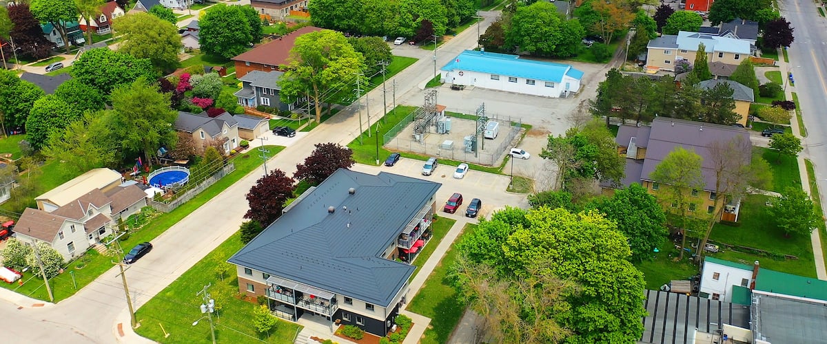 An aerial view of a residential area with houses, a large blue building, and a swimming pool.