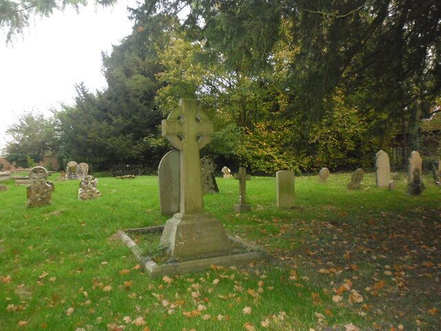 A cemetery with gravestones and a large Celtic cross.
