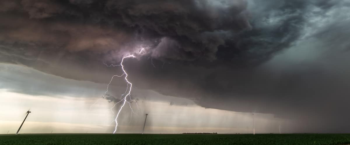 A stormy sky with lightning and a green field.