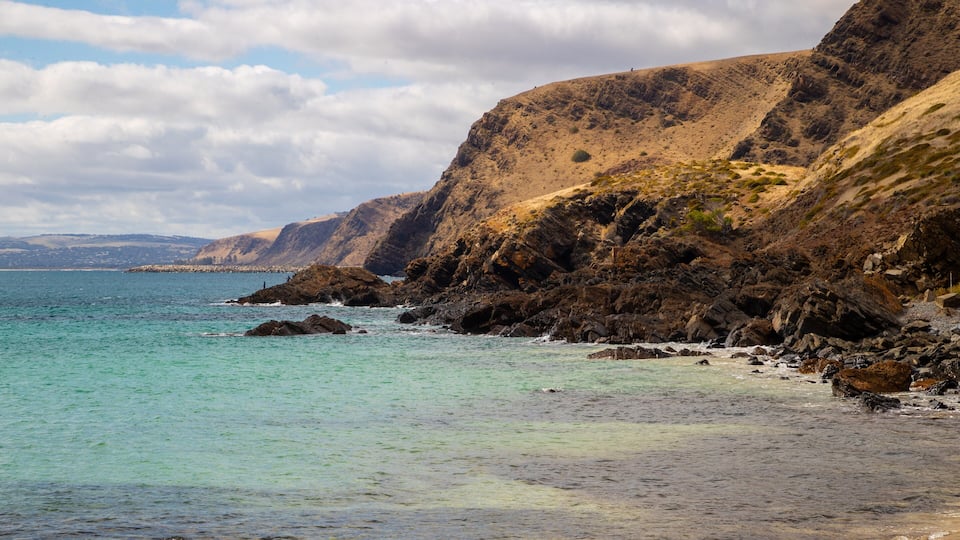 A coastal landscape with rocky cliffs and clear turquoise waters.