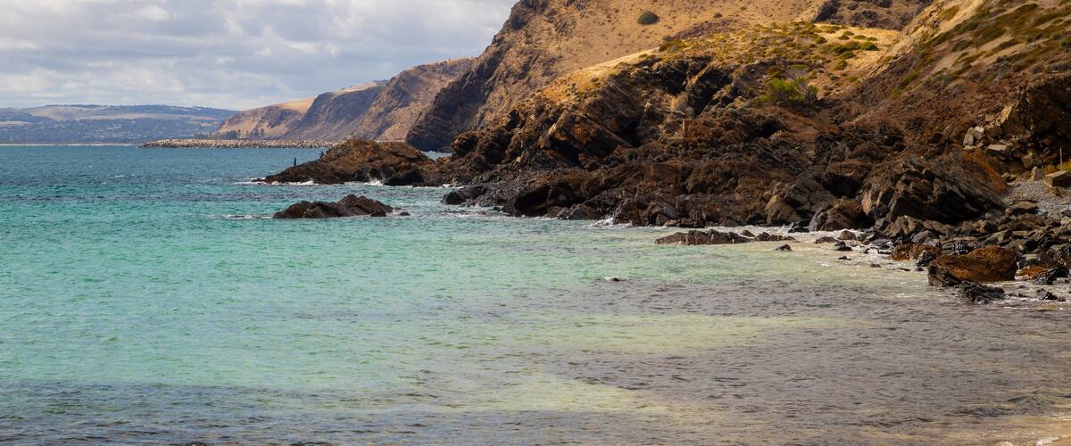 A coastal landscape with rocky cliffs and clear turquoise waters.