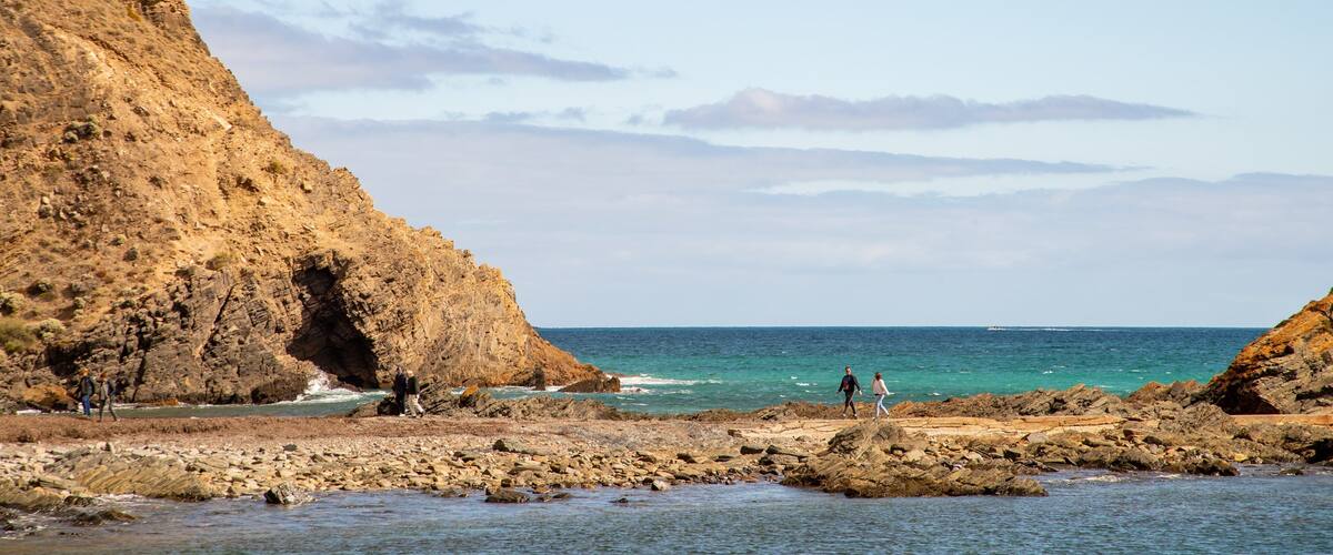 A rocky coastline with cliffs and a clear blue sea.