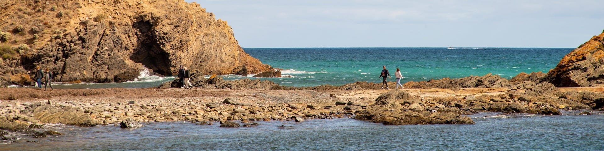 A rocky coastline with cliffs and a clear blue sea.