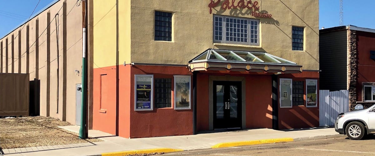 A building with a sign reading "Palace Theater" and a small awning.