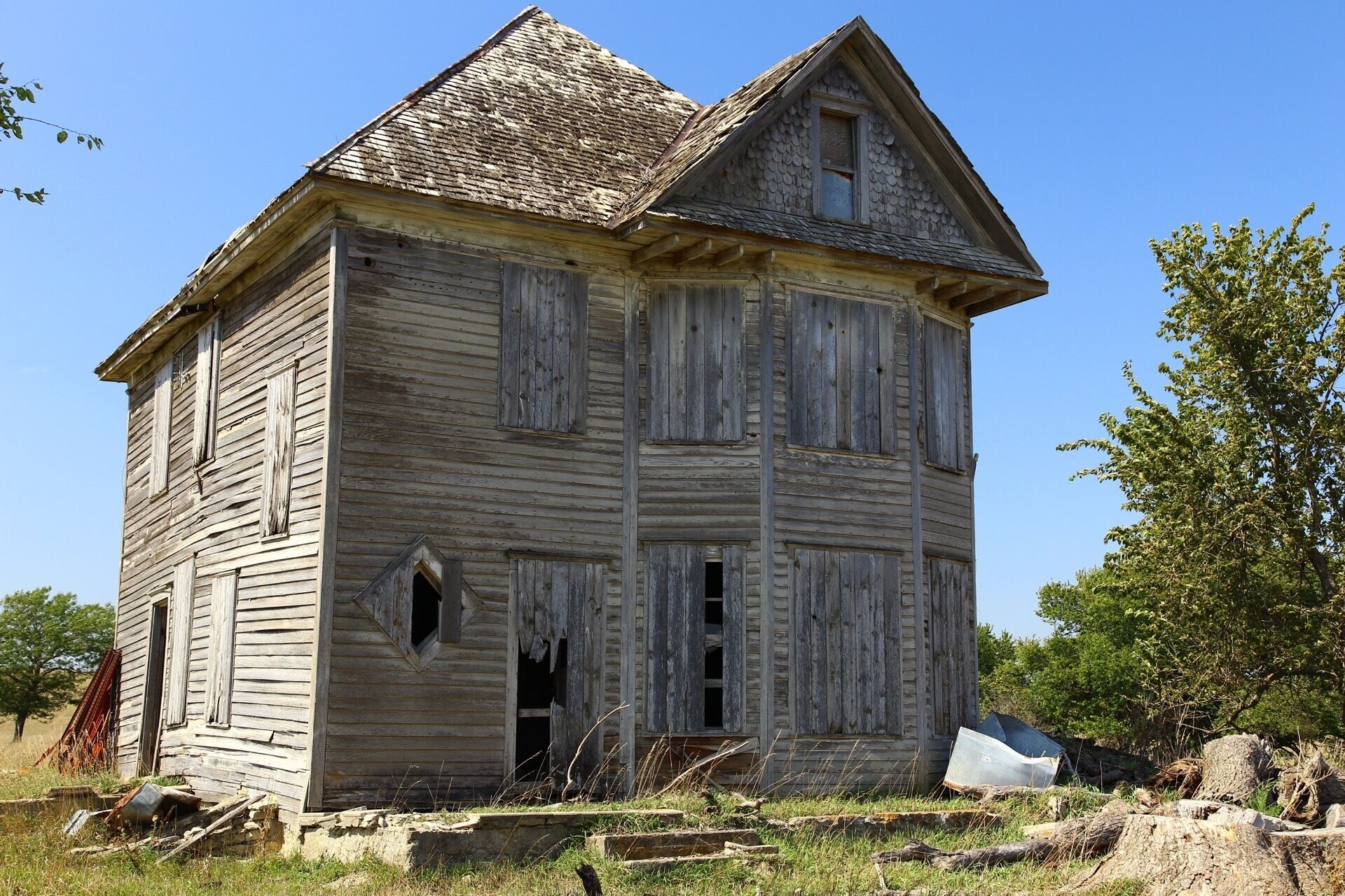 An old wooden house with boarded-up windows and a dilapidated roof.