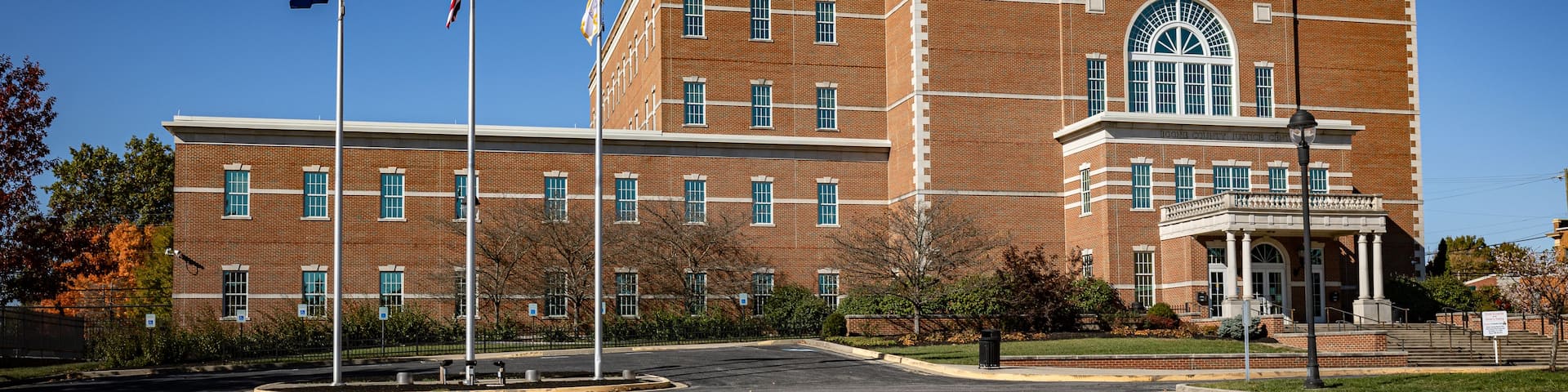 A courthouse with a brick facade, multiple flags, and a clear blue sky.