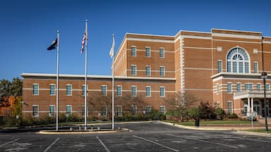 A courthouse with a brick facade, multiple flags, and a clear blue sky.