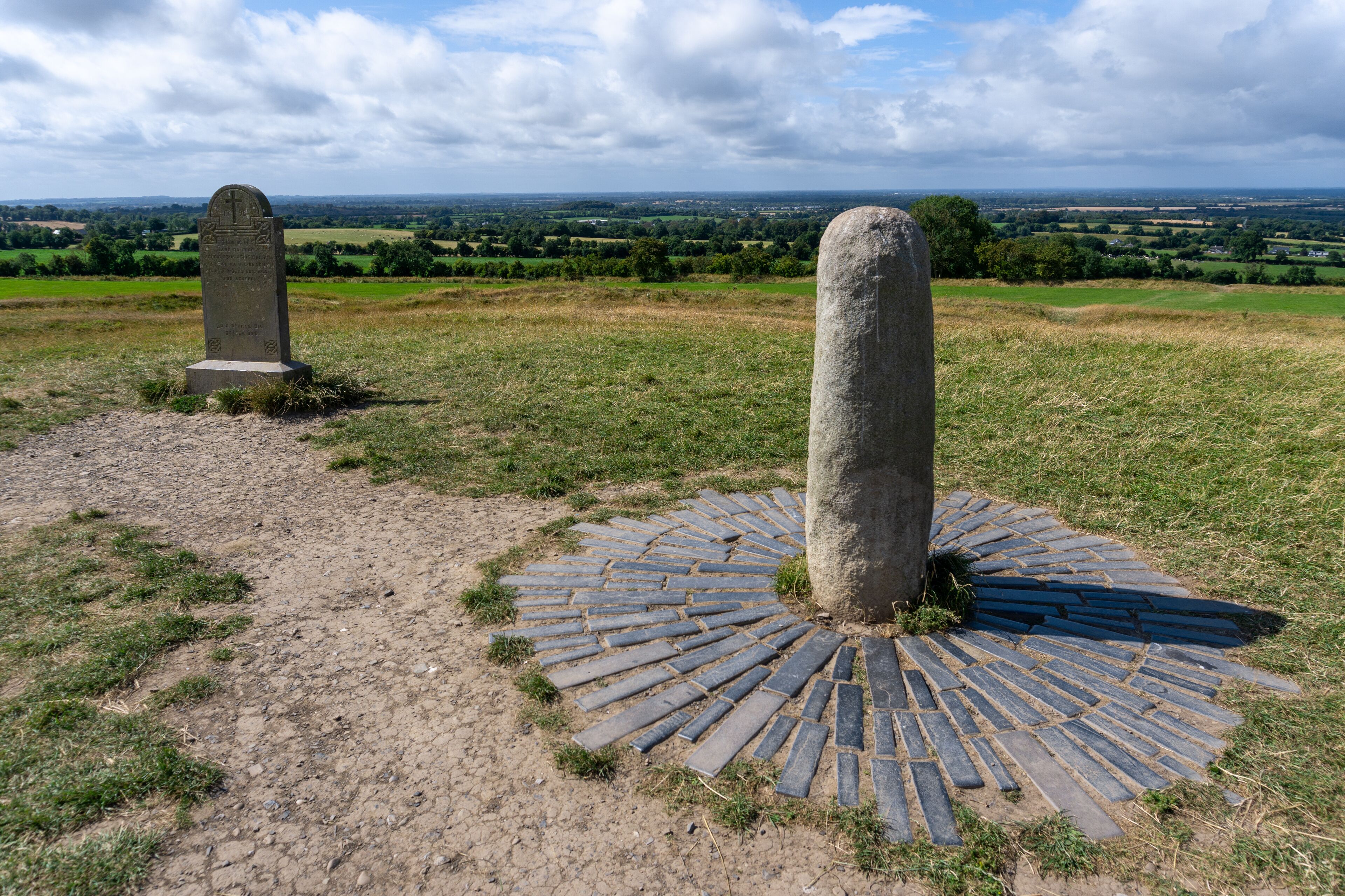 A stone monument with a circular stone pavement and another monument in the background.