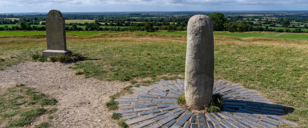 A stone monument with a circular stone pavement and another monument in the background.