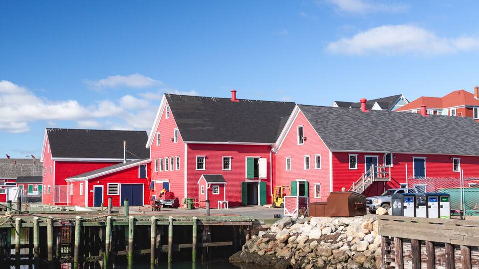 A red building with a dock extending into calm water.