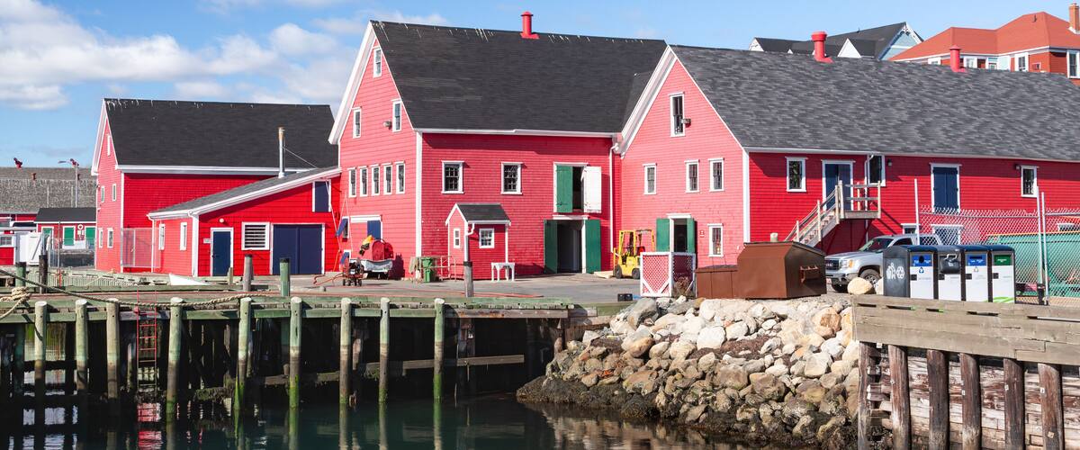 A red building with a dock extending into calm water.