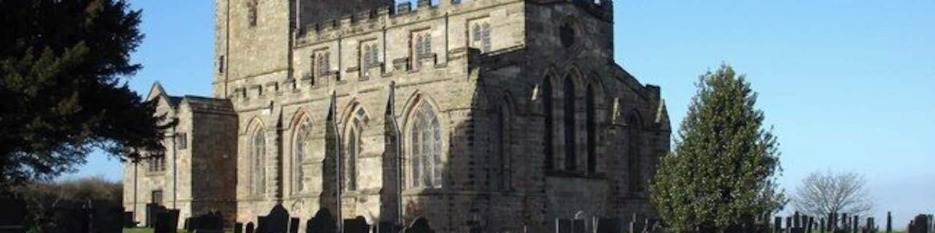 Breedon Priory Church, Breedon on The Hill, Leicestershire, viewed from the southeast on a sunny December morning. The churchyard is full of 18th and 19th century gravestones which, being made from Swithland Slate, are still completely legible.