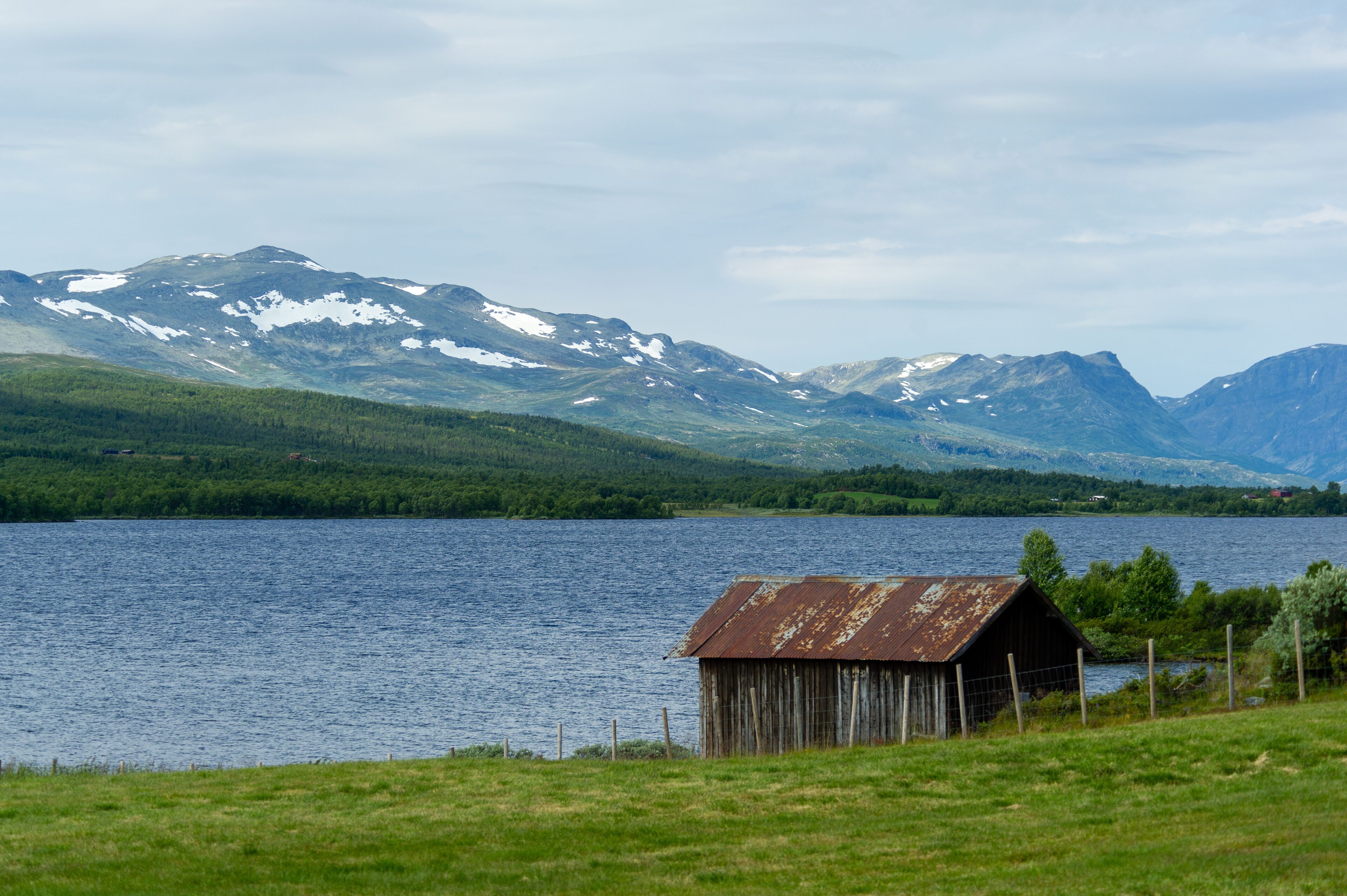 A lake with mountains in the background and a small wooden structure in the foreground.