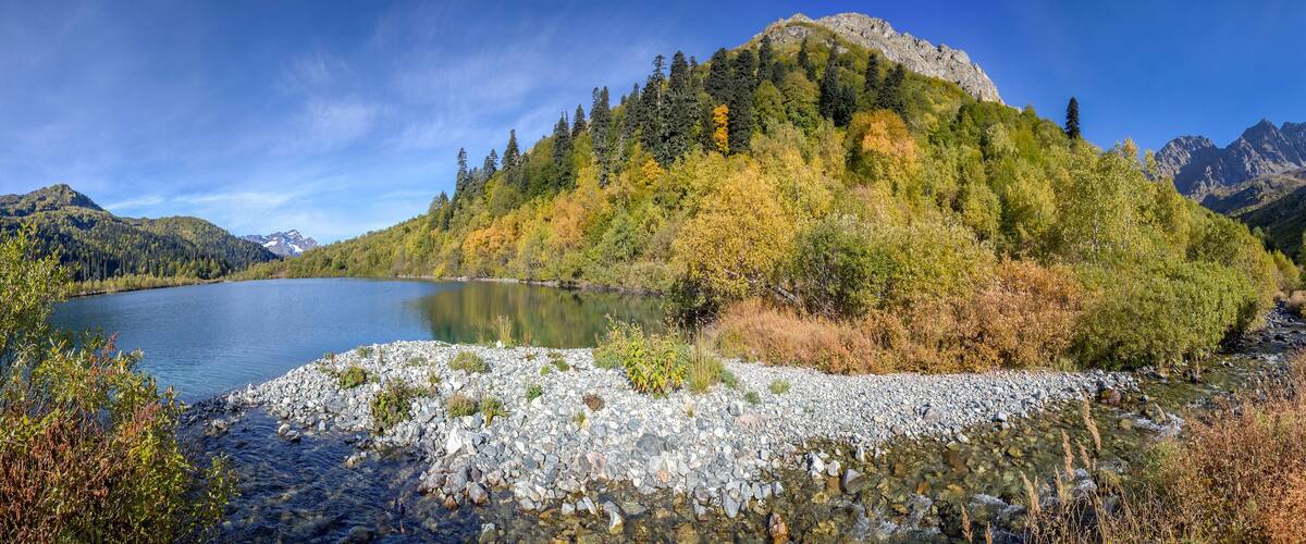 A mountain lake surrounded by autumn foliage and rocky terrain.