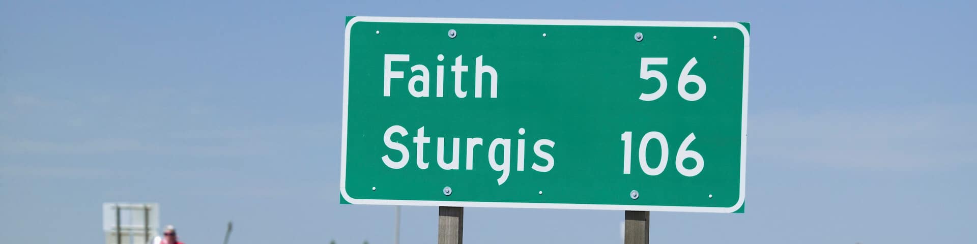 State Highway 34 with highway sign for Sturgis South Dakota and motorcyclist's heading away from the 67th Annual Sturgis Motorcycle Rally, Sturgis, South Dakota, August 6-12, 2007