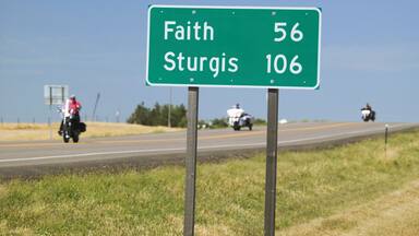 State Highway 34 with highway sign for Sturgis South Dakota and motorcyclist's heading away from the 67th Annual Sturgis Motorcycle Rally, Sturgis, South Dakota, August 6-12, 2007