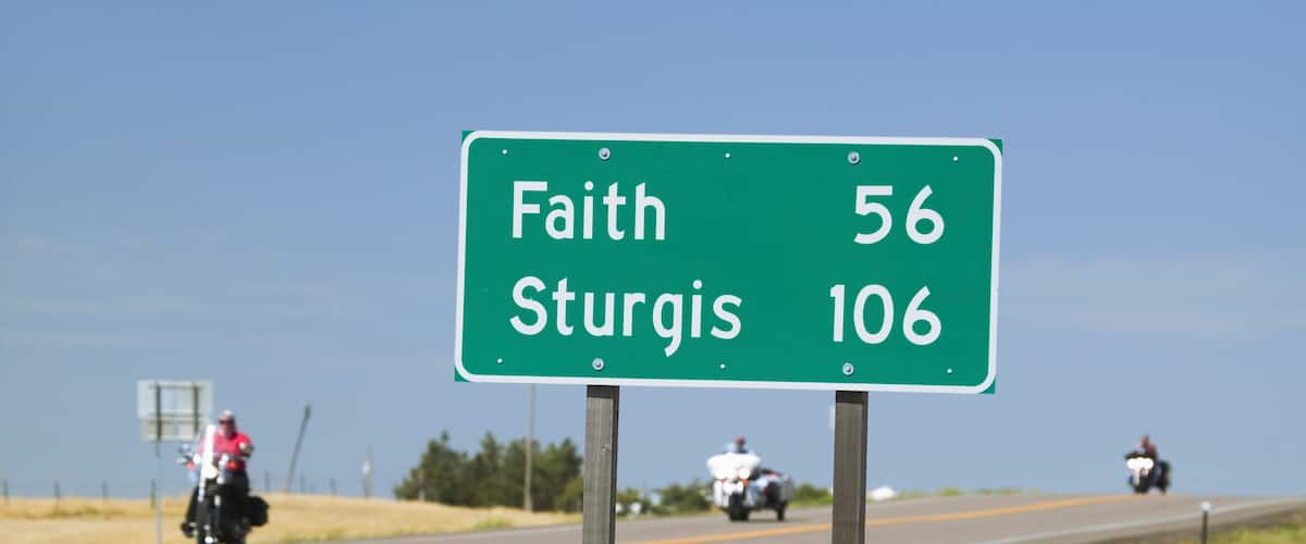 A highway sign with directions to Faith and Sturgis, indicating distances of 56 and 106 miles respectively.