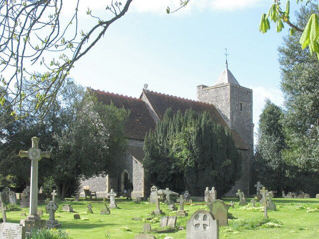 A church with a stone tower and crosses in a cemetery.
