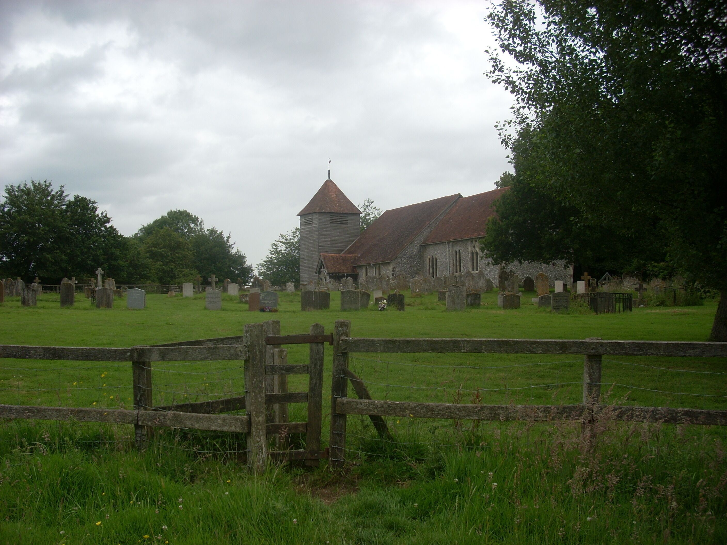 A church with a tower and a cemetery in the foreground.