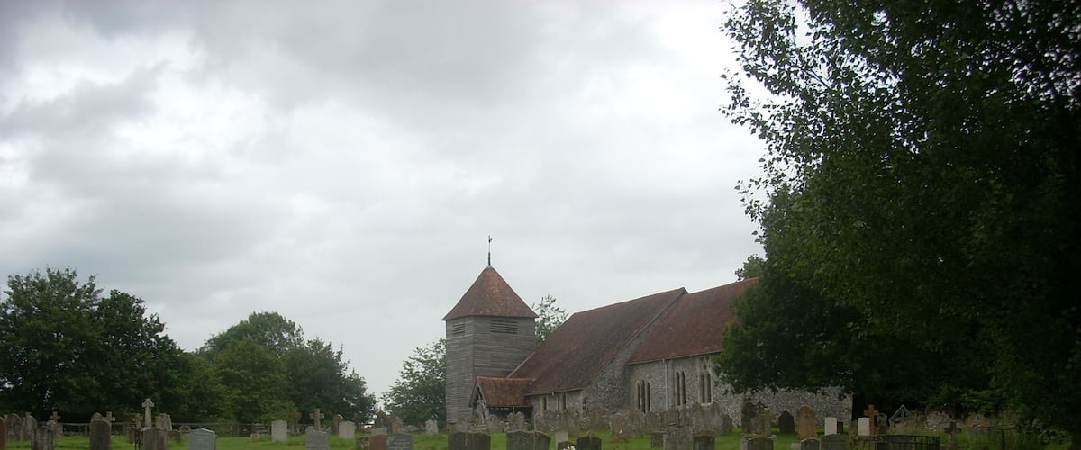 A church with a tower and a cemetery in the foreground.
