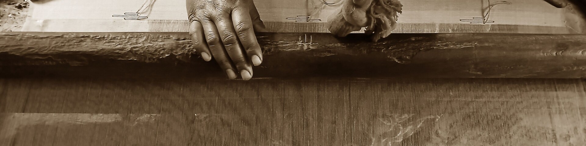 Una mano tejiendo en un telar.