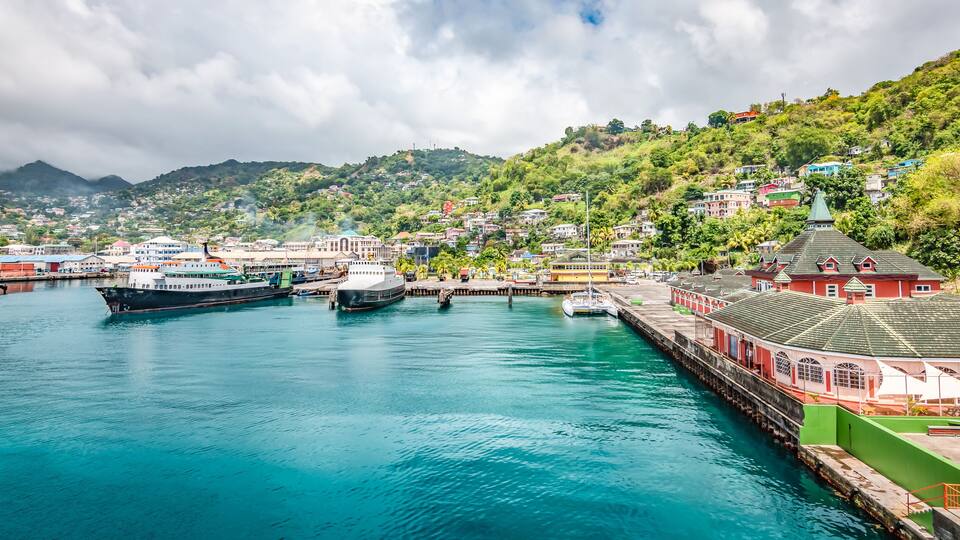 A harbor with boats, a pier, and buildings on a hillside.