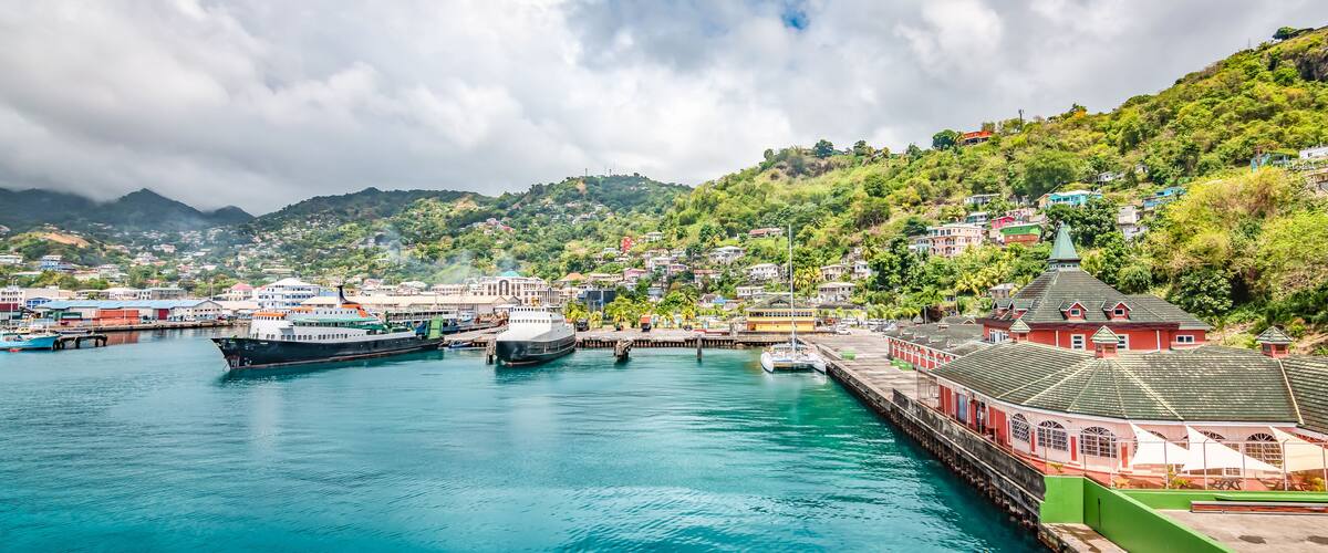 A harbor with boats, a pier, and buildings on a hillside.