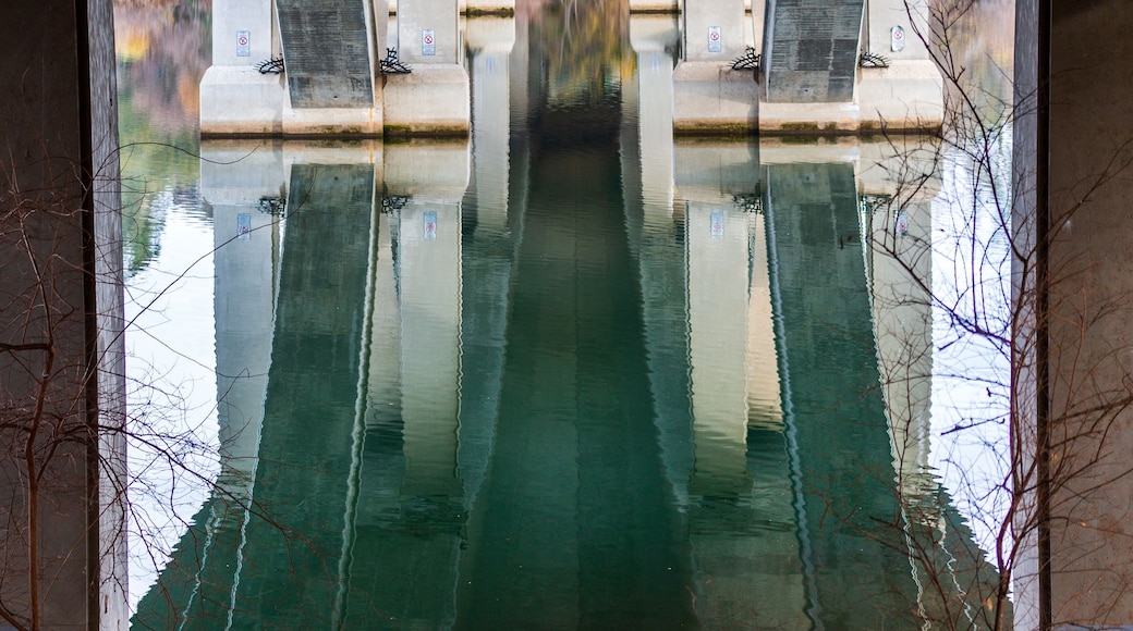 A stone bridge with arches over a calm river reflecting the structure.