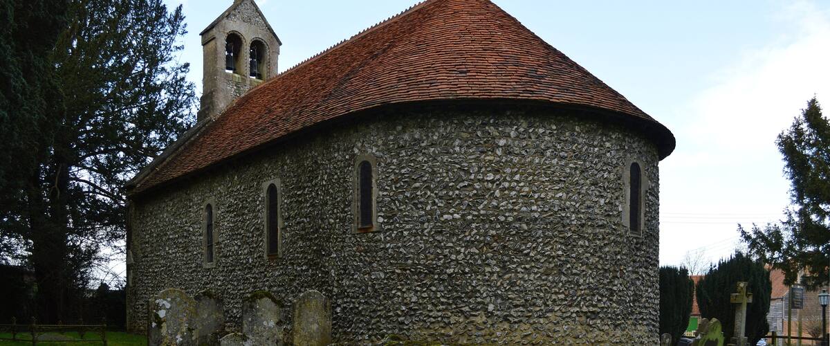 A stone church with a bell tower and a red-tiled roof.