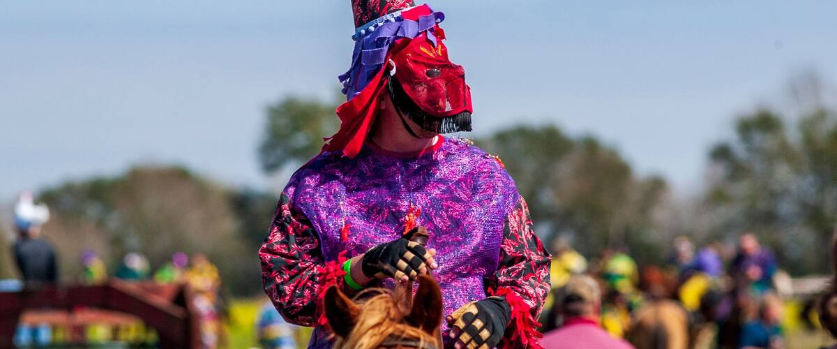 A person in a colorful costume with a pointed hat, standing in a crowd.