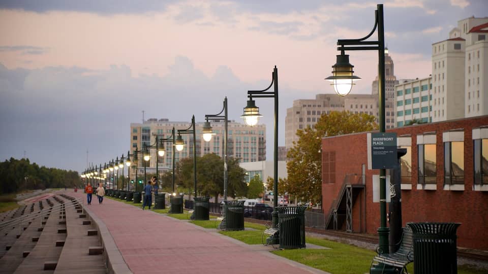 A city street with a red brick building labeled "Riverfront Plaza" and a row of street lamps.